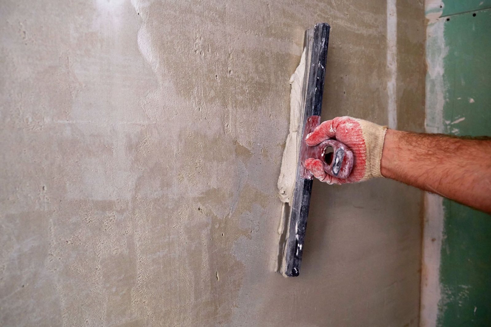 Pleister wordt met een spaan op een muur aangebracht